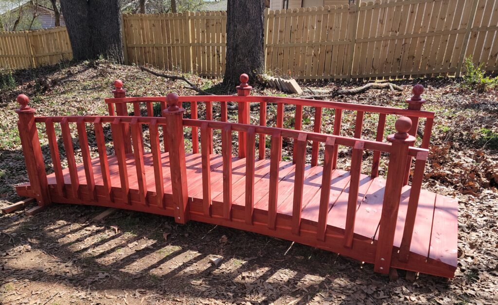 12-foot handcrafted cedar spindle rail bridge with decorative posts, built for gardens and outdoor landscapes