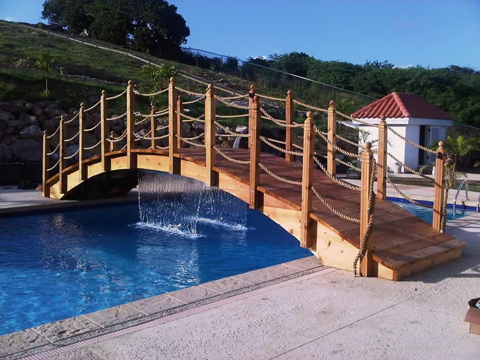 Handcrafted red cedar rope rail garden bridge installed over a pool, custom built in the USA by Redwood Bridges.
